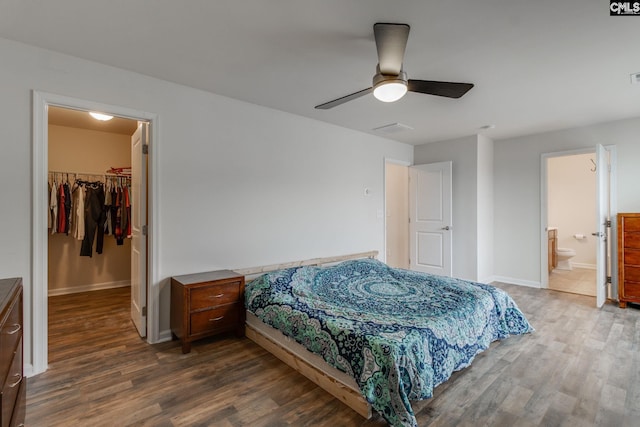 bedroom featuring connected bathroom, ceiling fan, a spacious closet, dark wood-type flooring, and a closet