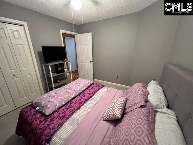 bedroom with a closet, a textured ceiling, ceiling fan, and carpet floors