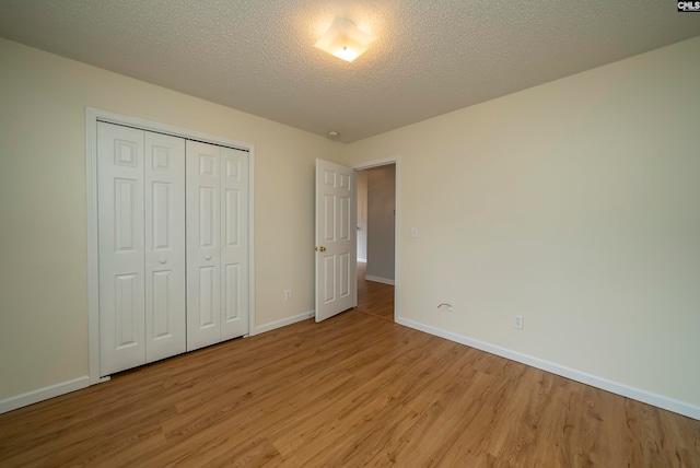 unfurnished bedroom with a textured ceiling, a closet, and light wood-type flooring