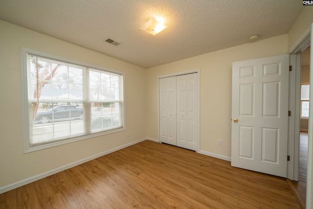 unfurnished bedroom featuring light hardwood / wood-style floors, a textured ceiling, and a closet