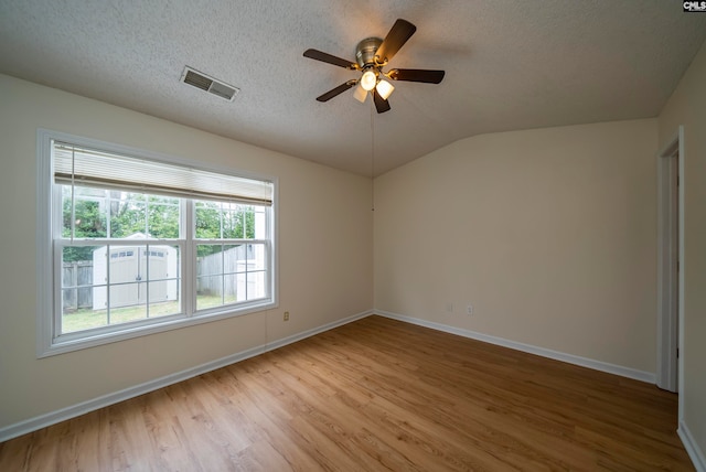 empty room featuring light hardwood / wood-style floors, a textured ceiling, ceiling fan, and vaulted ceiling