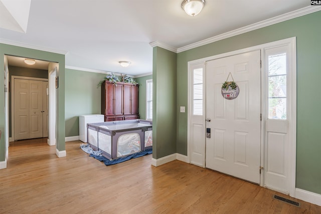 entryway with light hardwood / wood-style flooring and crown molding