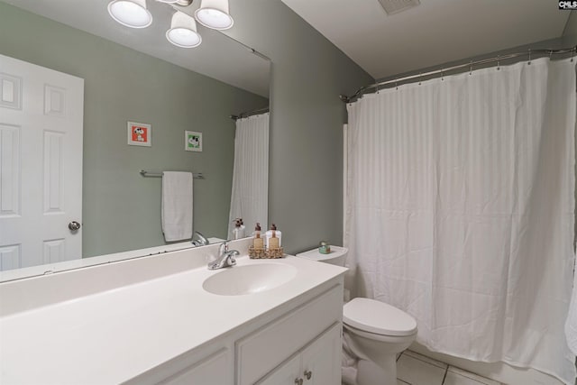 bathroom with toilet, large vanity, and tile floors