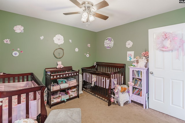 bedroom featuring a crib, light colored carpet, and ceiling fan