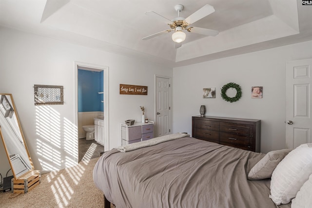 bedroom featuring carpet, a tray ceiling, ceiling fan, and ensuite bathroom