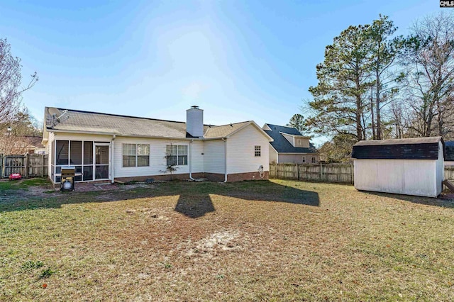 rear view of property with a storage unit, a sunroom, and a yard