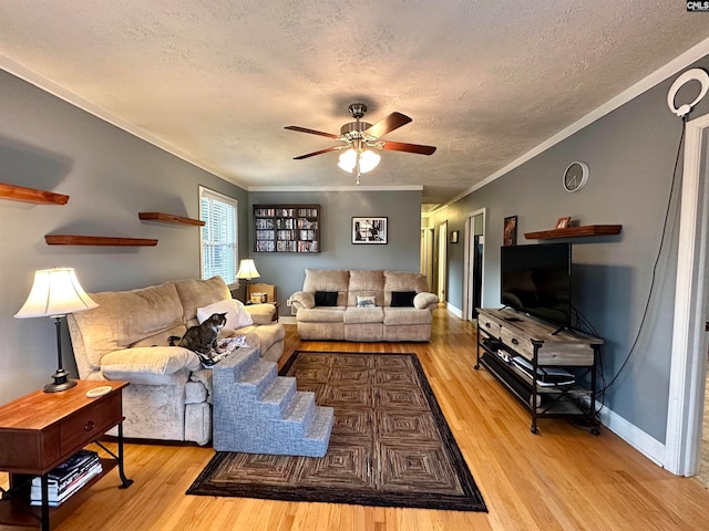 living room with ceiling fan, a textured ceiling, light hardwood / wood-style floors, and crown molding