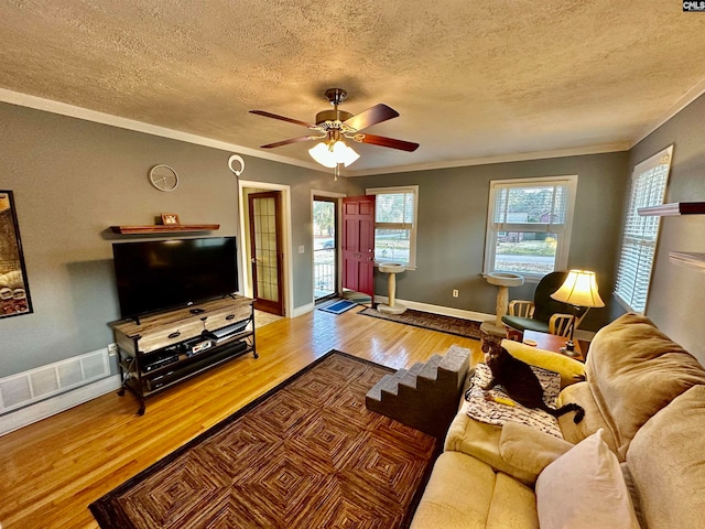 living room featuring a healthy amount of sunlight, hardwood / wood-style floors, ceiling fan, and crown molding