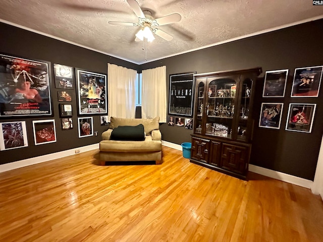 living area with a textured ceiling, ceiling fan, and light hardwood / wood-style flooring