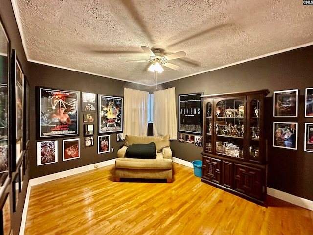 sitting room with a textured ceiling, ceiling fan, and light wood-type flooring