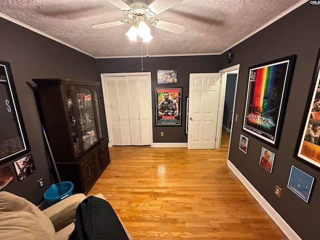 interior space with light hardwood / wood-style flooring, ceiling fan, crown molding, and a textured ceiling