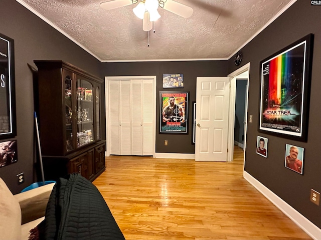 interior space featuring ornamental molding, light hardwood / wood-style floors, ceiling fan, and a textured ceiling