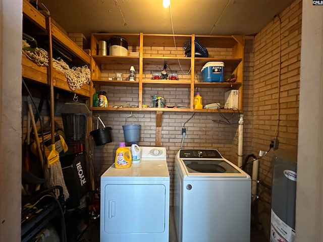 washroom featuring brick wall, water heater, and independent washer and dryer