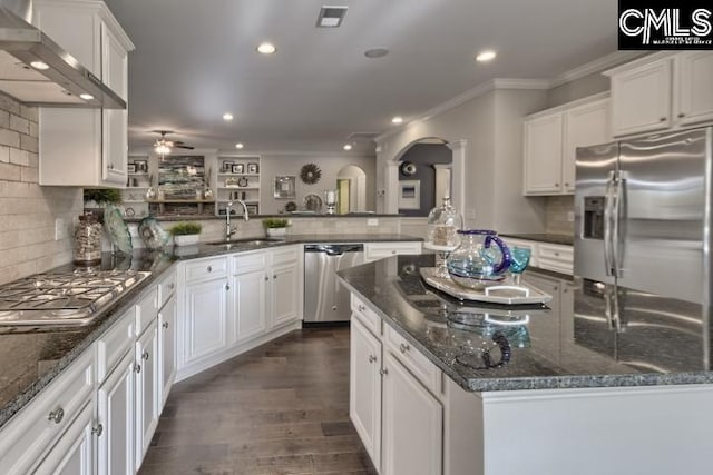 kitchen featuring stainless steel appliances, wall chimney exhaust hood, white cabinets, dark stone countertops, and dark hardwood / wood-style floors