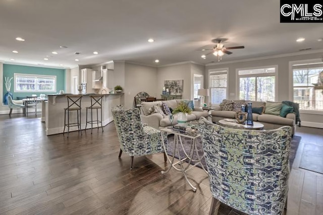 living room featuring dark hardwood / wood-style flooring, ceiling fan, crown molding, and a healthy amount of sunlight