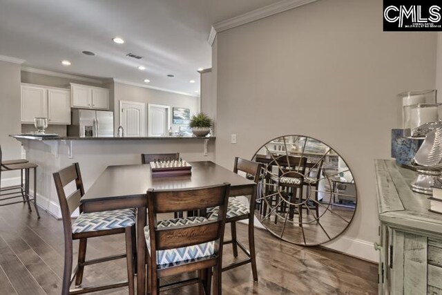 dining room with crown molding and dark wood-type flooring