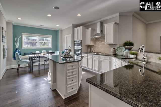 kitchen featuring wall chimney exhaust hood, a kitchen island, white cabinets, and dark hardwood / wood-style floors