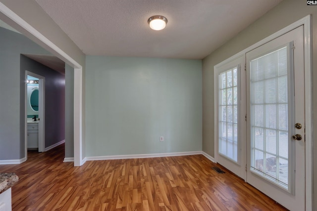 empty room with a textured ceiling and wood-type flooring