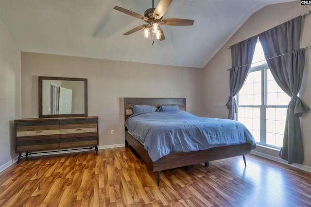 bedroom with lofted ceiling, ceiling fan, multiple windows, and hardwood / wood-style flooring