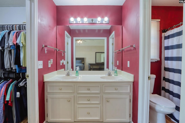 bathroom with toilet, ceiling fan, and dual vanity