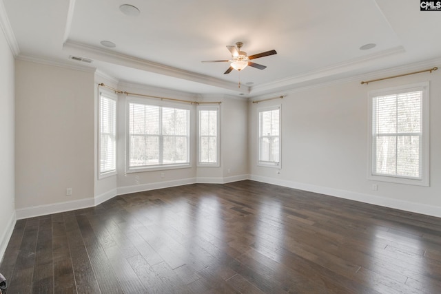 empty room with a tray ceiling, ceiling fan, dark wood-type flooring, and crown molding