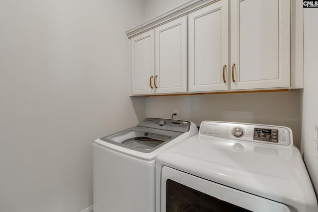 clothes washing area with cabinets and washer and clothes dryer