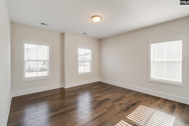 empty room with dark hardwood / wood-style flooring and a healthy amount of sunlight