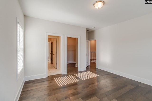 unfurnished bedroom featuring a walk in closet, a closet, and light hardwood / wood-style flooring