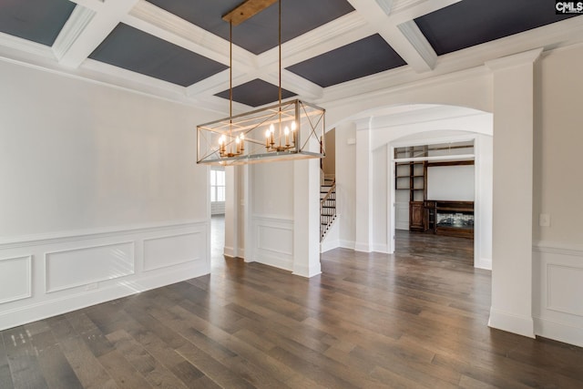 unfurnished dining area featuring coffered ceiling, an inviting chandelier, dark hardwood / wood-style floors, ornamental molding, and beam ceiling