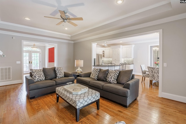 living room featuring french doors, ceiling fan, crown molding, light hardwood / wood-style flooring, and a tray ceiling