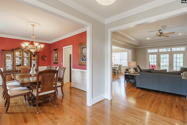 dining space featuring crown molding, ceiling fan with notable chandelier, and light wood-type flooring