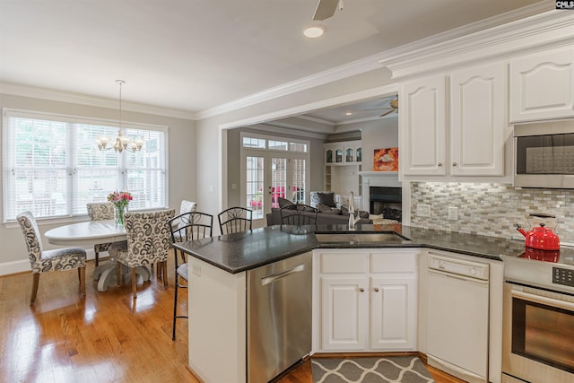 kitchen featuring appliances with stainless steel finishes, light hardwood / wood-style floors, ceiling fan with notable chandelier, sink, and white cabinets