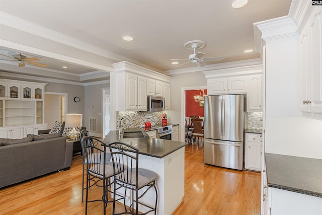 kitchen featuring white cabinets, backsplash, appliances with stainless steel finishes, and ceiling fan with notable chandelier