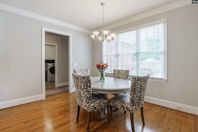 dining room featuring an inviting chandelier, ornamental molding, washer / dryer, and light hardwood / wood-style floors