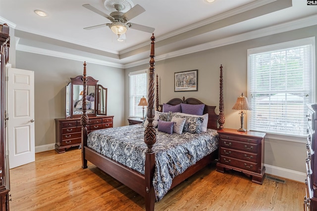 bedroom with a tray ceiling, ceiling fan, ornamental molding, and light hardwood / wood-style flooring