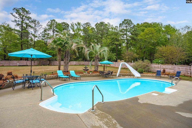 view of pool featuring a lawn, a patio, and a water slide