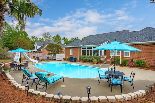 view of pool with a water slide and a patio area