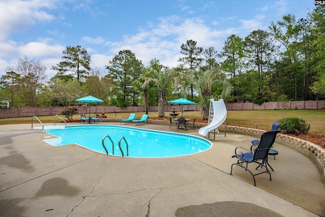 view of pool with a patio, a water slide, and a lawn