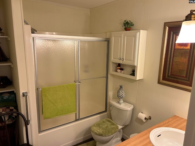 full bathroom featuring enclosed tub / shower combo, toilet, ornamental molding, and sink