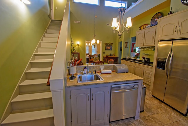 kitchen featuring a notable chandelier, appliances with stainless steel finishes, hanging light fixtures, and light tile flooring