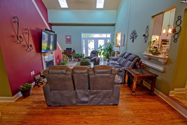 living room featuring hardwood / wood-style flooring, french doors, a towering ceiling, and a chandelier