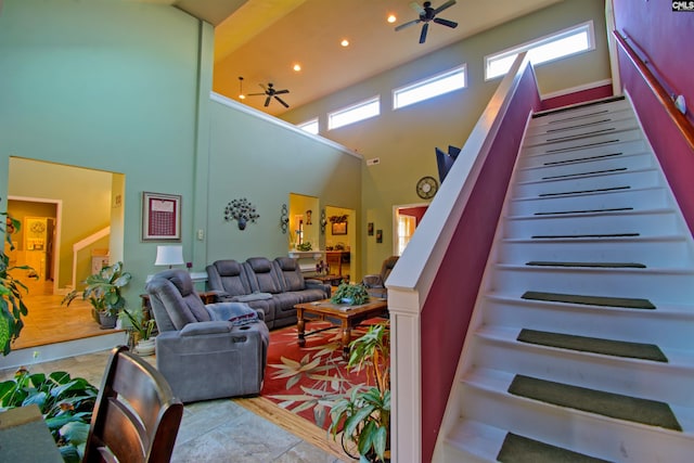 living room featuring a towering ceiling, plenty of natural light, light hardwood / wood-style flooring, and ceiling fan