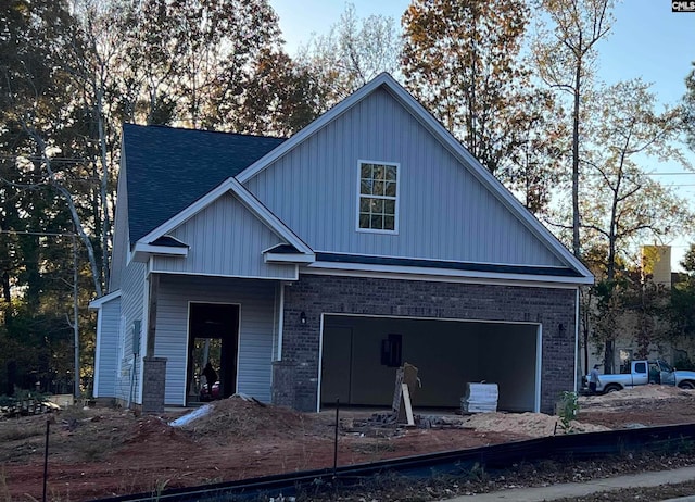 view of front of house featuring an attached garage, roof with shingles, and brick siding