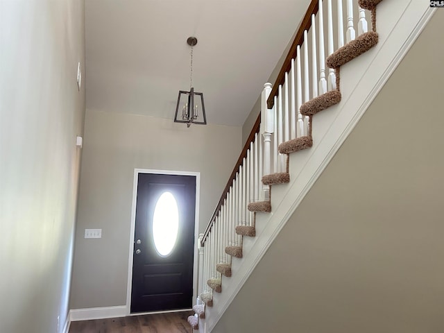 foyer entrance with stairs, baseboards, and dark wood-type flooring