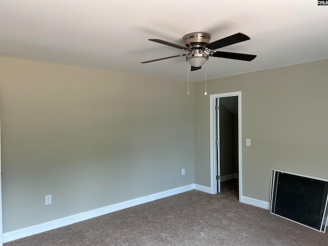 empty room with a ceiling fan, dark colored carpet, and baseboards