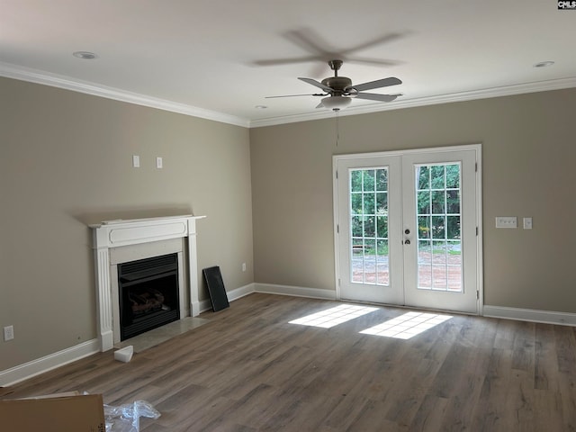 unfurnished living room with baseboards, a fireplace with flush hearth, wood finished floors, crown molding, and french doors