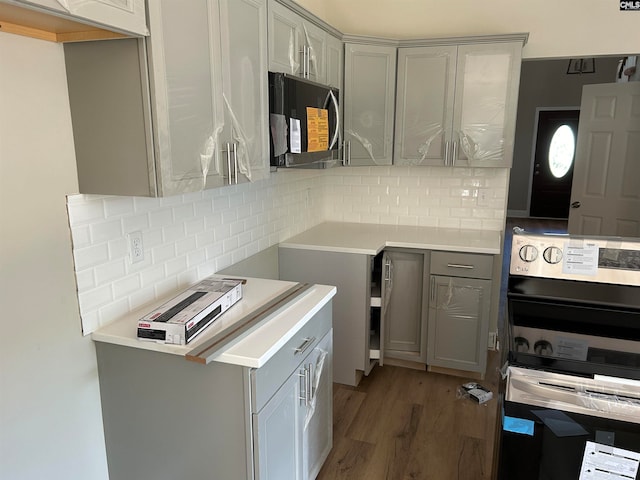 kitchen with wall oven, wood finished floors, gray cabinets, light countertops, and backsplash