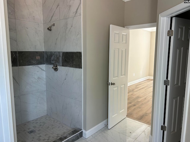 bathroom featuring marble finish floor, a marble finish shower, and baseboards