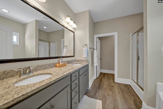 bathroom with vanity with extensive cabinet space, walk in shower, wood-type flooring, and dual sinks