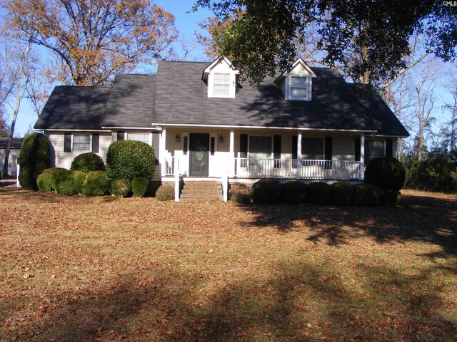 cape cod home featuring a front yard and a porch